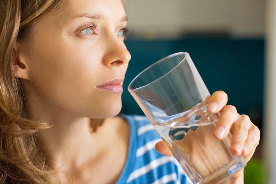 Closeup portrait of pensive young attractive woman drinking water from glass. Fresh drinking water concept. Side view.